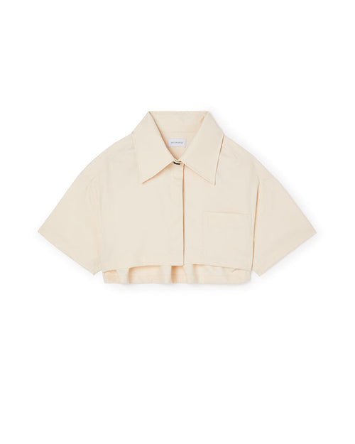 A cropped beige cotton shirt with a sharp collar and short sleeves, featuring a single chest pocket and button closure.