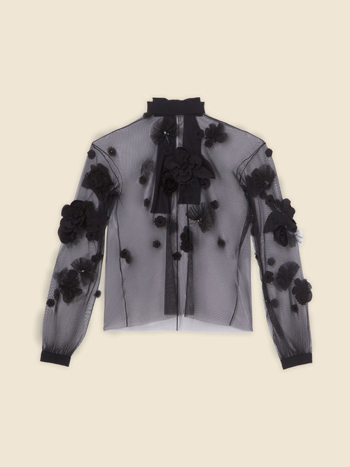 Sheer black blouse with floral appliqués, long sleeves, and high neck against a neutral background.