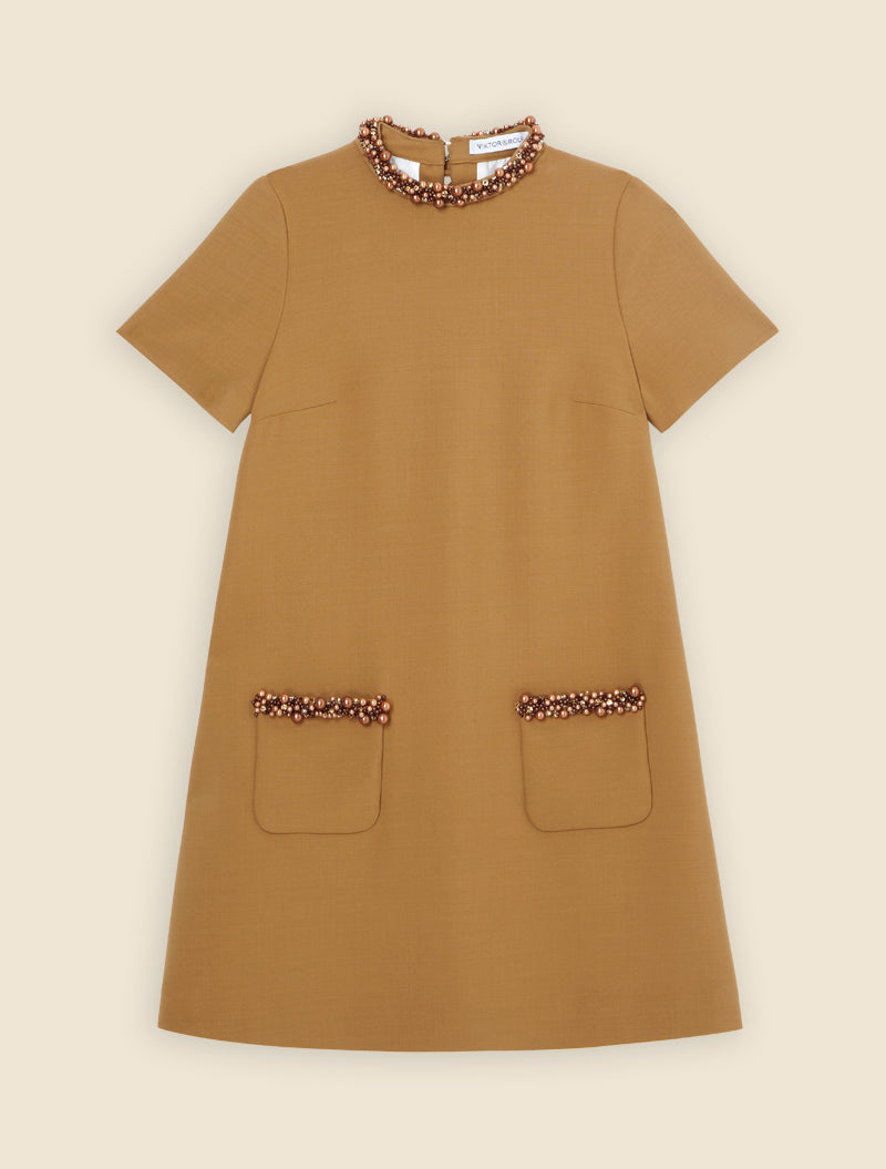 Elegant mustard wool dress featuring pearl embellishments on the neckline and pocket edges, with short sleeves.