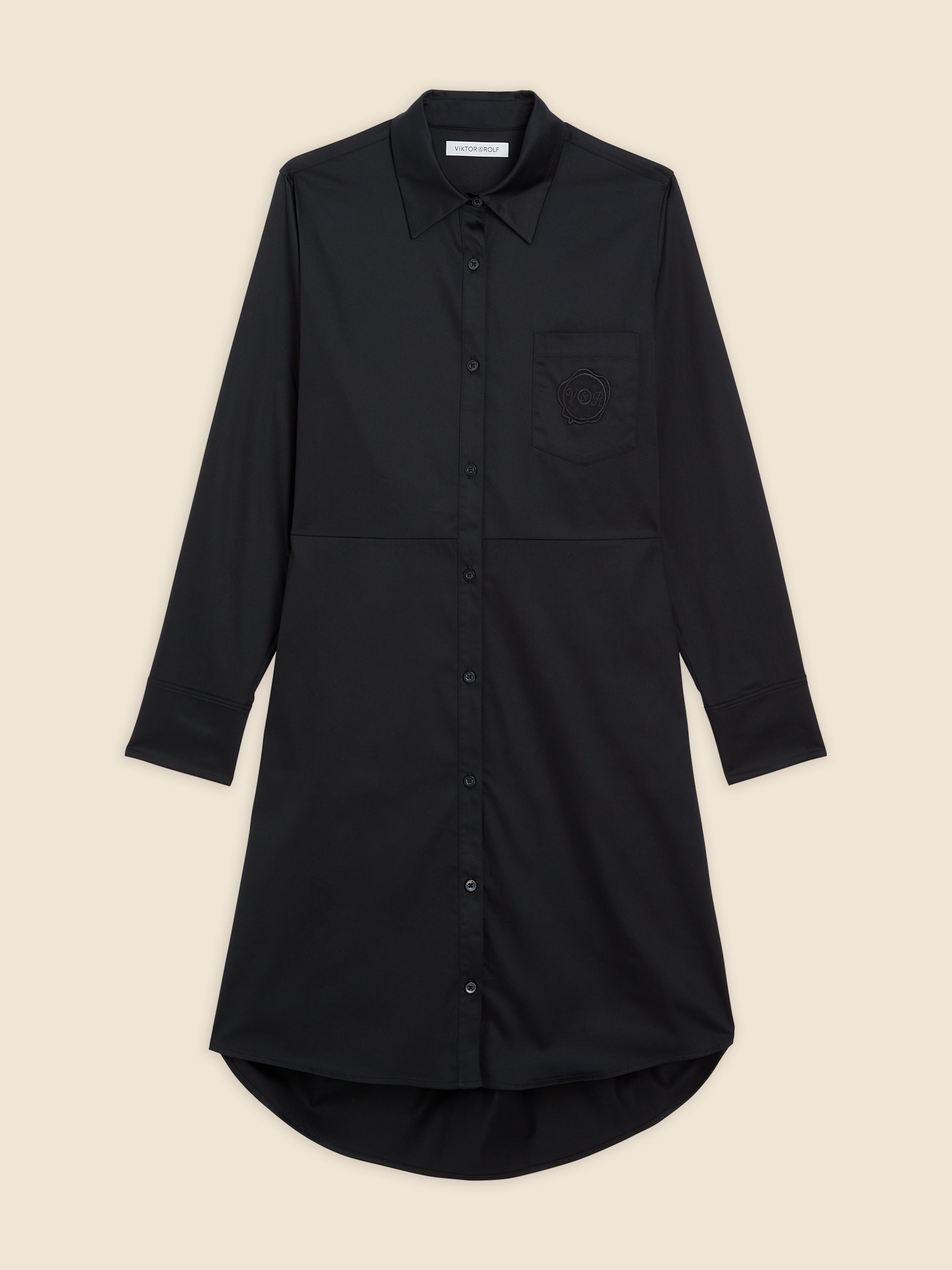 Black long-sleeve shirt dress with button-down front and curved hem, featuring a subtle embroidered skull on chest pocket.