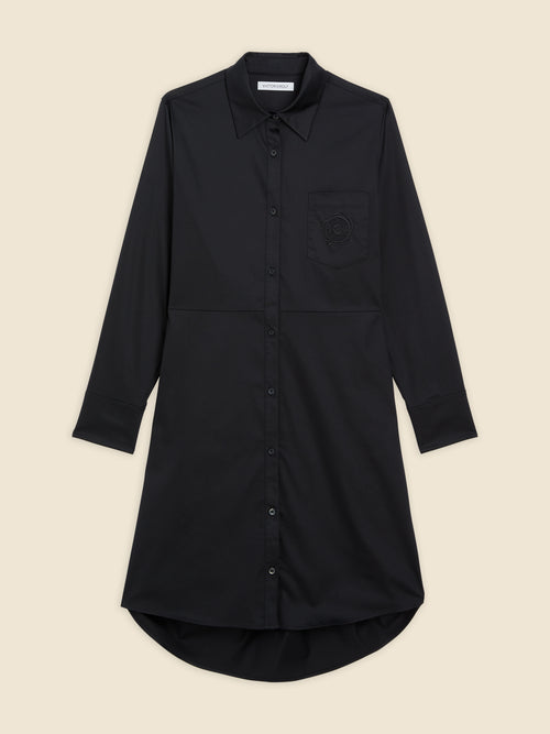 Black long-sleeve shirt dress with button-down front and curved hem, featuring a subtle embroidered skull on chest pocket.