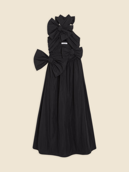 Elegant black dress with oversized bow details, featuring a sleeveless design and A-line silhouette, displayed on a beige background.