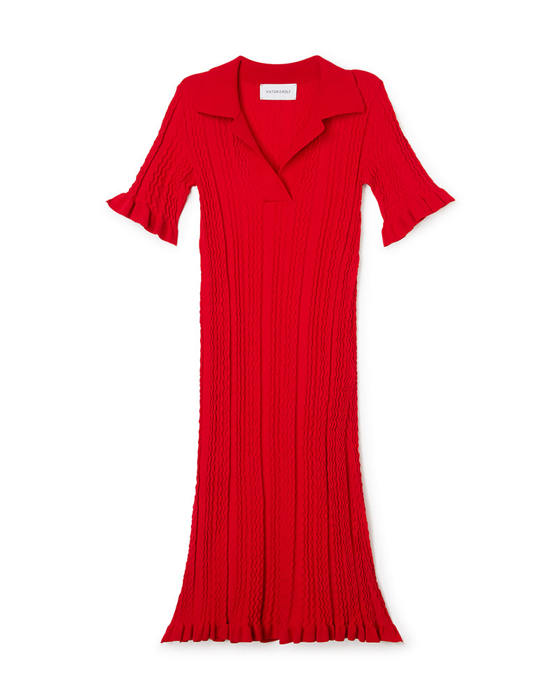 Red knitted dress featuring wavy textured pattern and flared sleeves, with a classic collar and flowing silhouette.