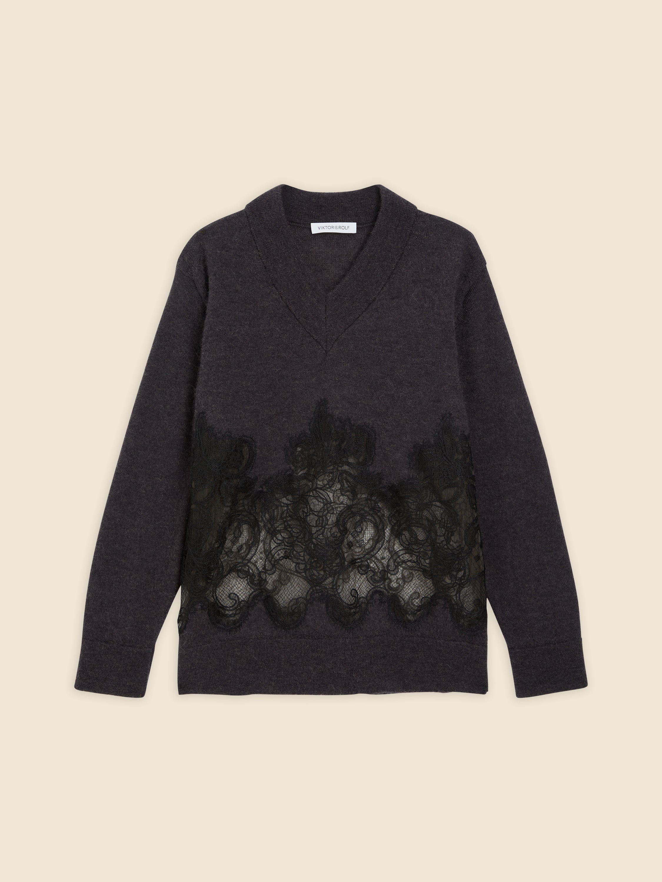Dark gray sweater with intricate black lace detailing across the front, featuring a deep V-neck and long sleeves.