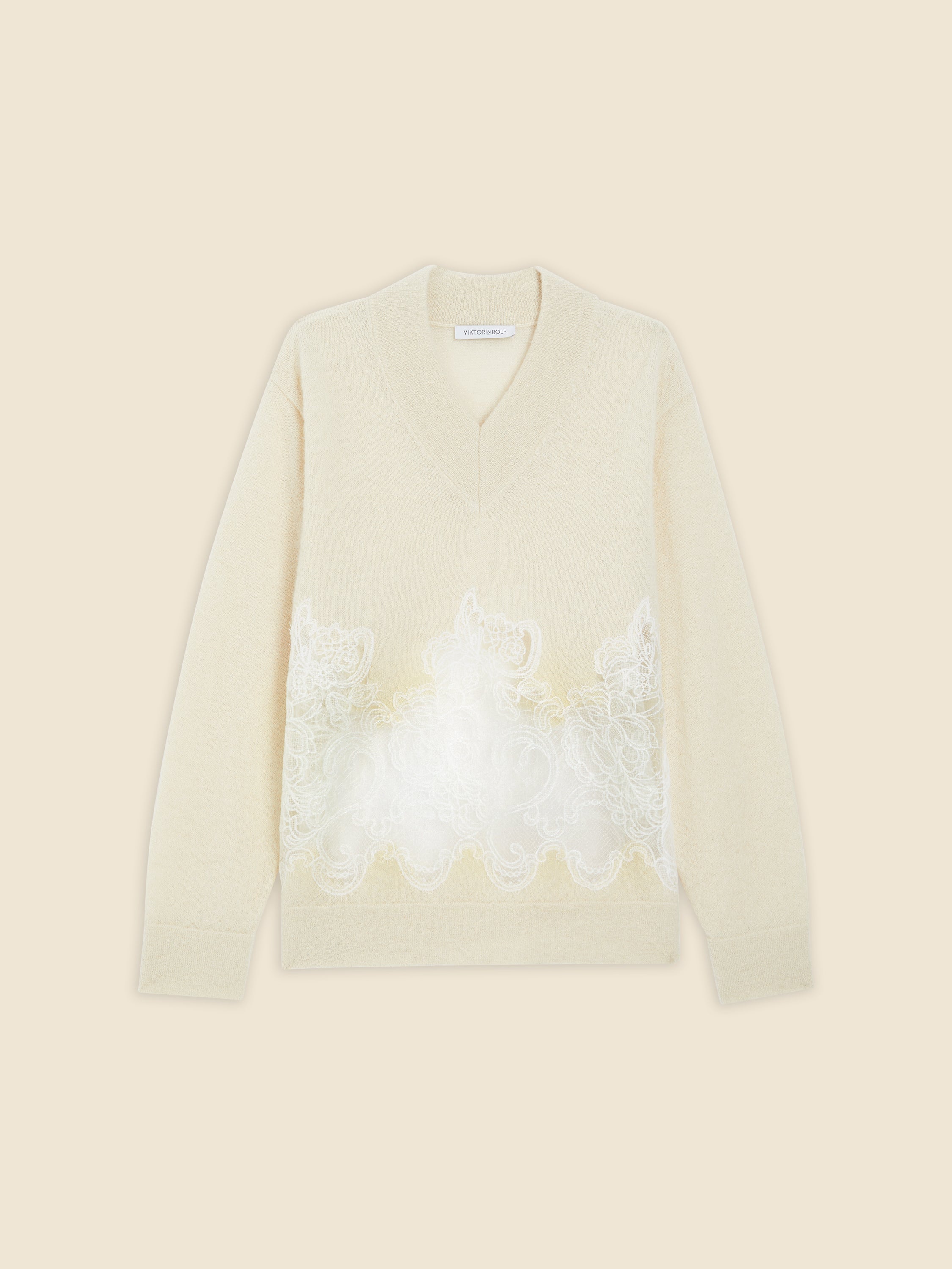 Cream V-neck sweater featuring intricate white lace embroidery, adding elegance and texture to the soft knit design.
