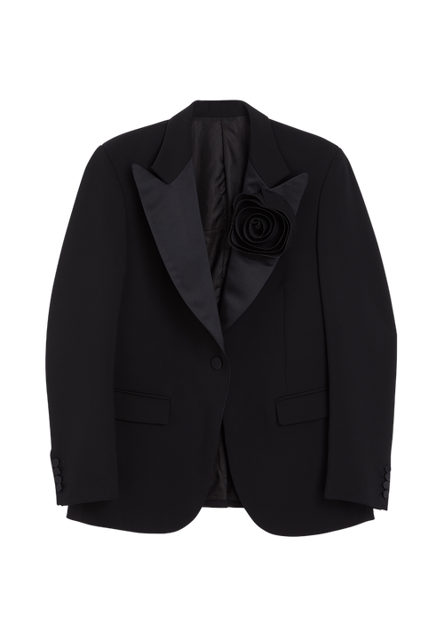 Elegant black tuxedo jacket with satin lapels, single button closure, and a striking fabric rosette on the left chest.