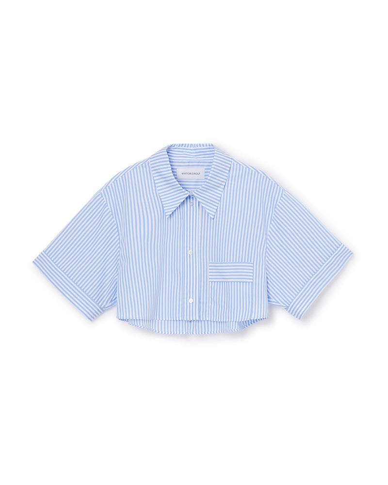 Cropped shirt with blue and white vertical stripes, featuring a classic collar, button closure, and a front pocket detail.