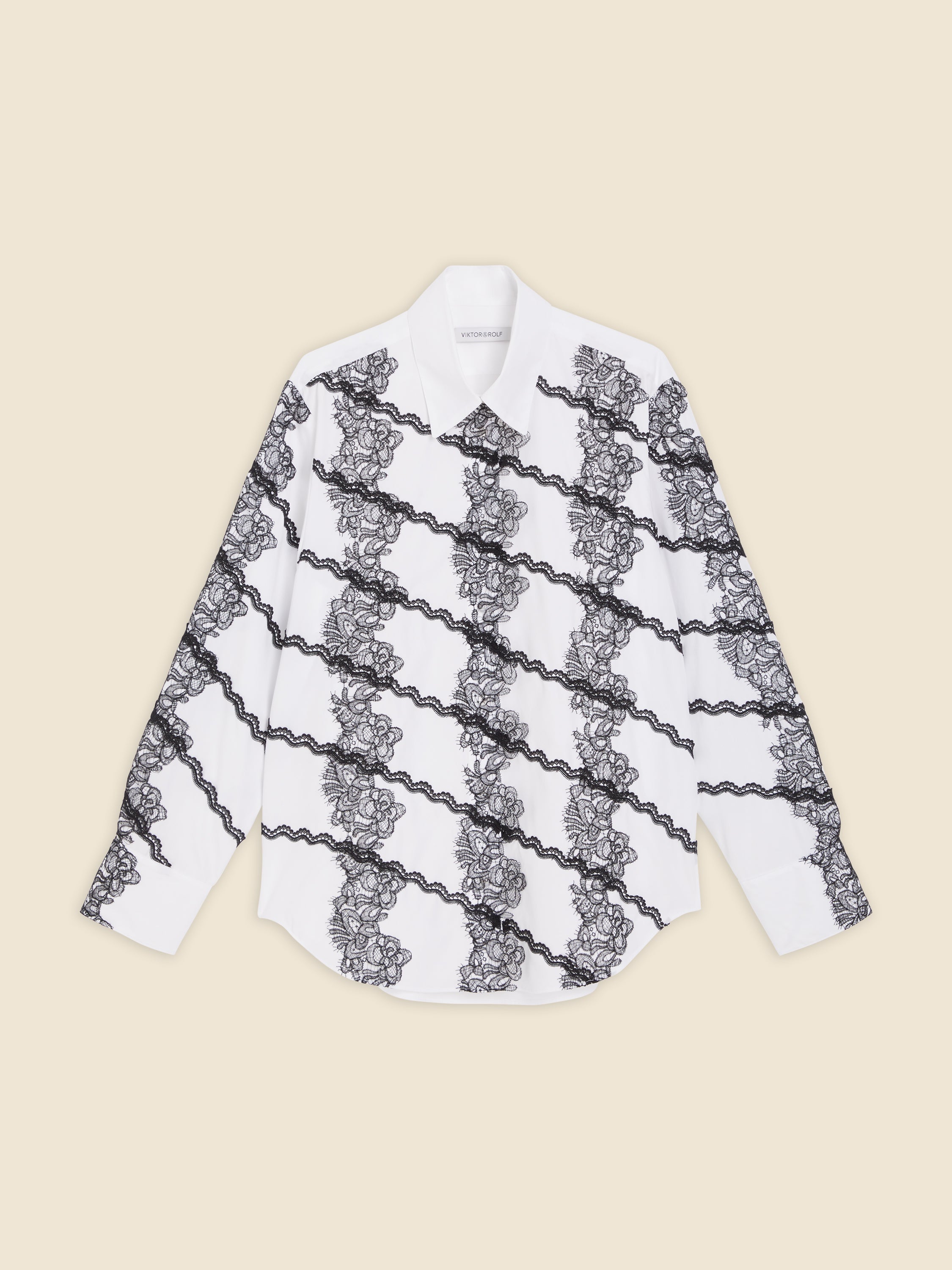 White cotton shirt with intricate black lace diagonal patterns, featuring classic collar and cuffed sleeves for elegant styling.