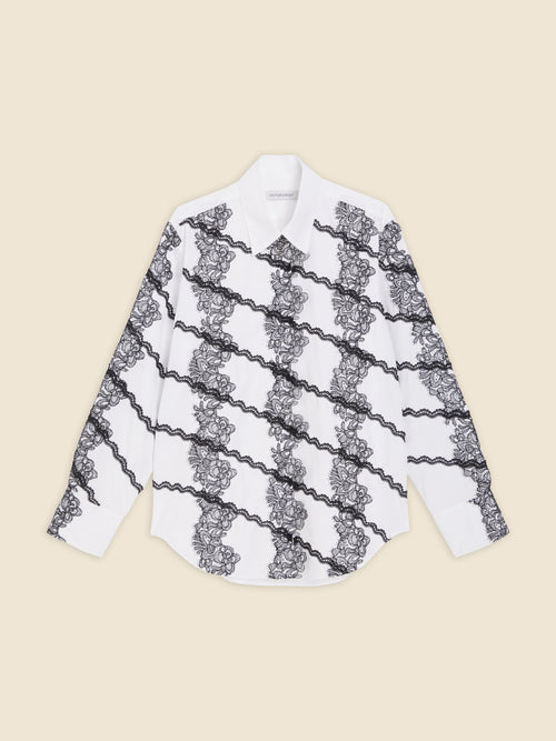 White cotton shirt with intricate black lace diagonal patterns, featuring classic collar and cuffed sleeves for elegant styling.