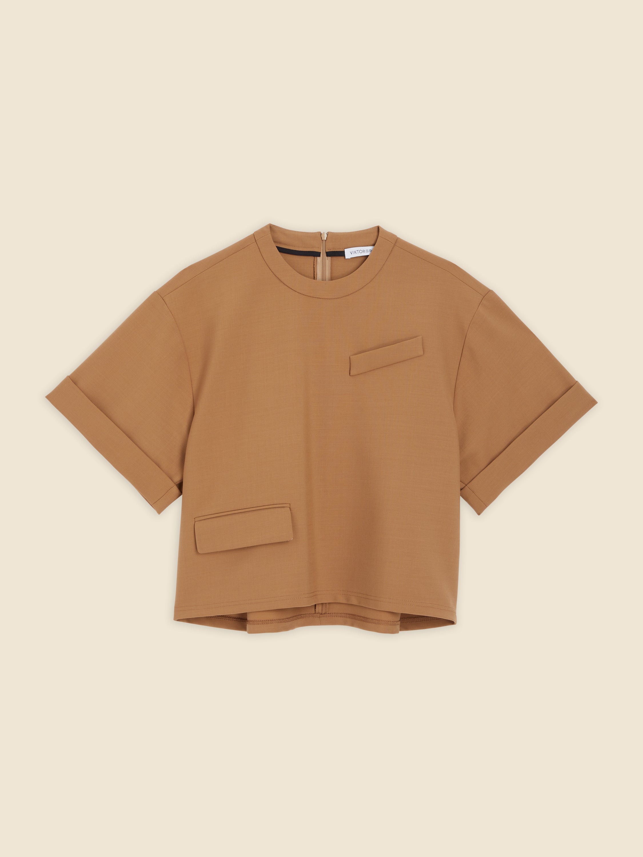 Boxy tan brown top with short sleeves, featuring unique pocket details and a subtle back zipper, crafted from soft material.