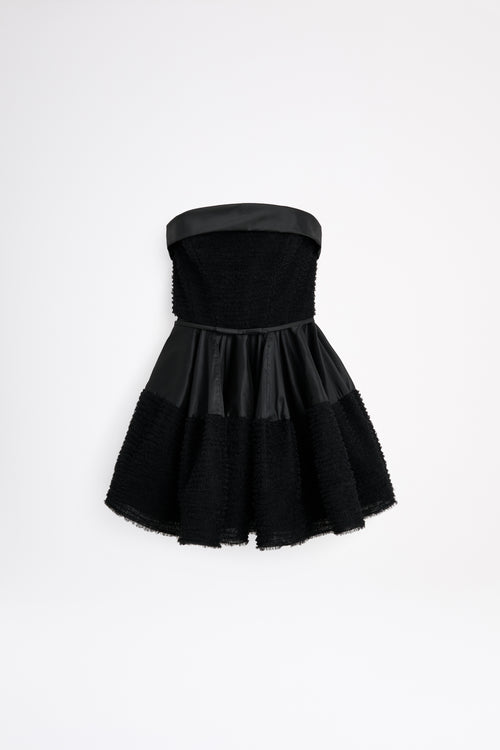 Black strapless dress with a textured skirt on a white background