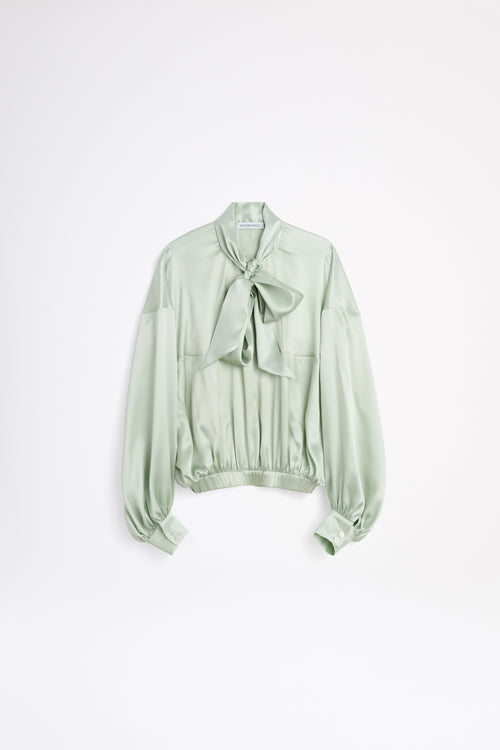 Light green blouse with a bow detail on a white background