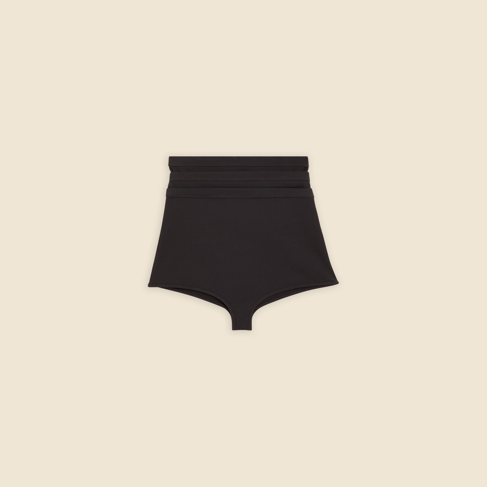 Black multi-layer shorts on a beige background.