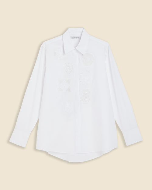White long-sleeved shirt featuring subtle embroidered patterns on the front, with a classic collar and buttoned cuffs.