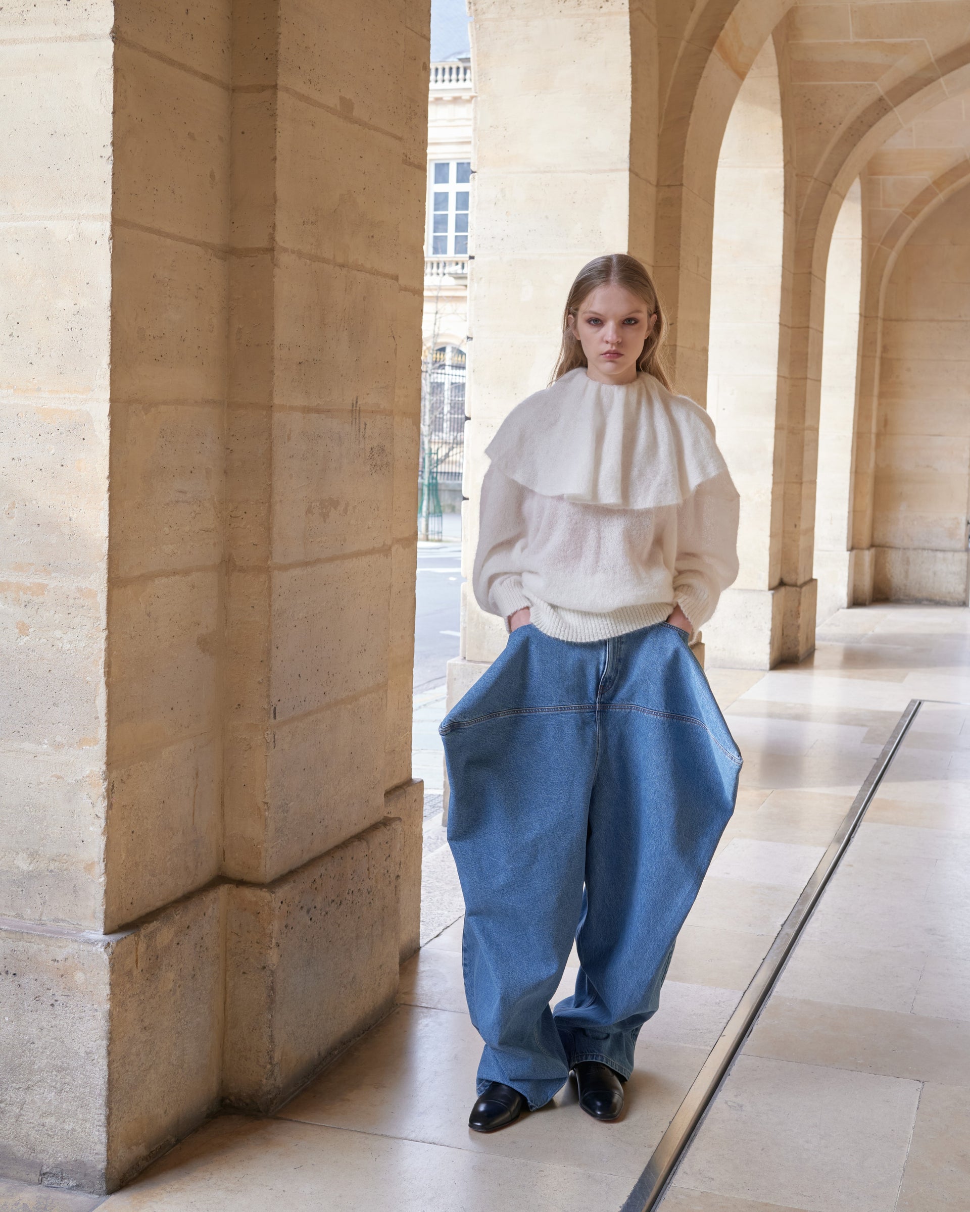 Model in the streets of Paris wearing a white knit sweater and light blue jeans