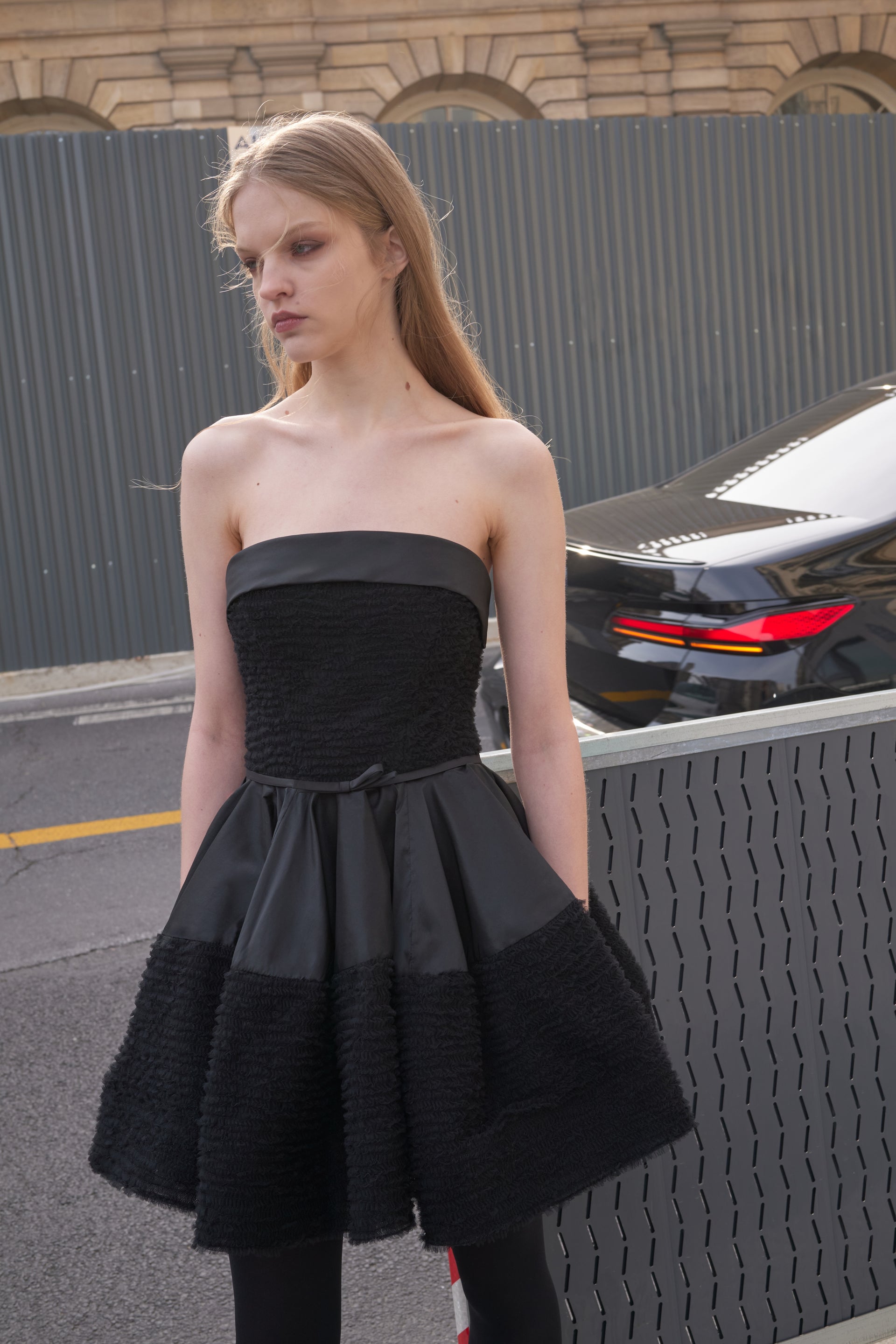 Model wearing a black tulle mini dress outside.