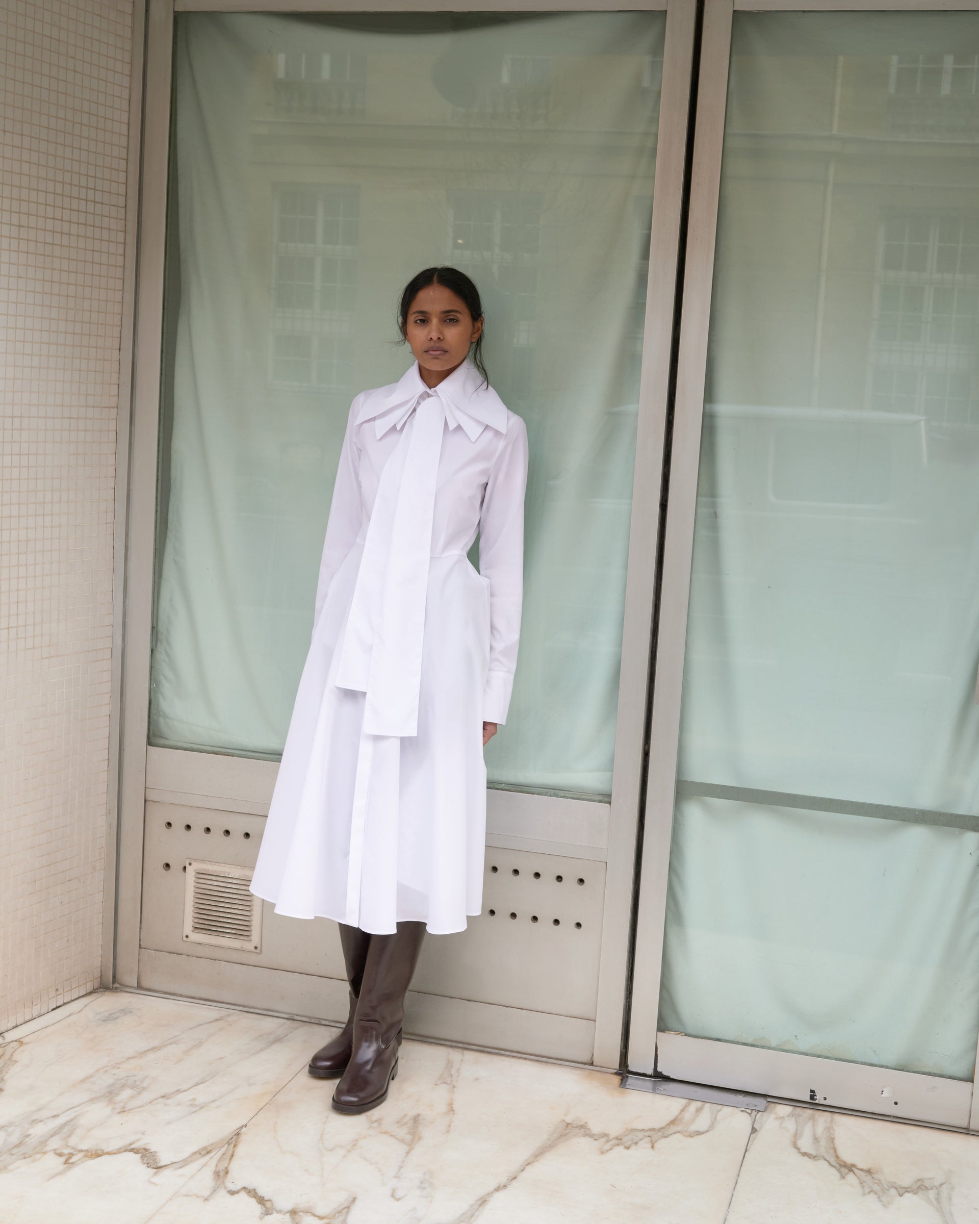 Model wearing a white shirt dress with a triple layered collar in the streets of Paris 