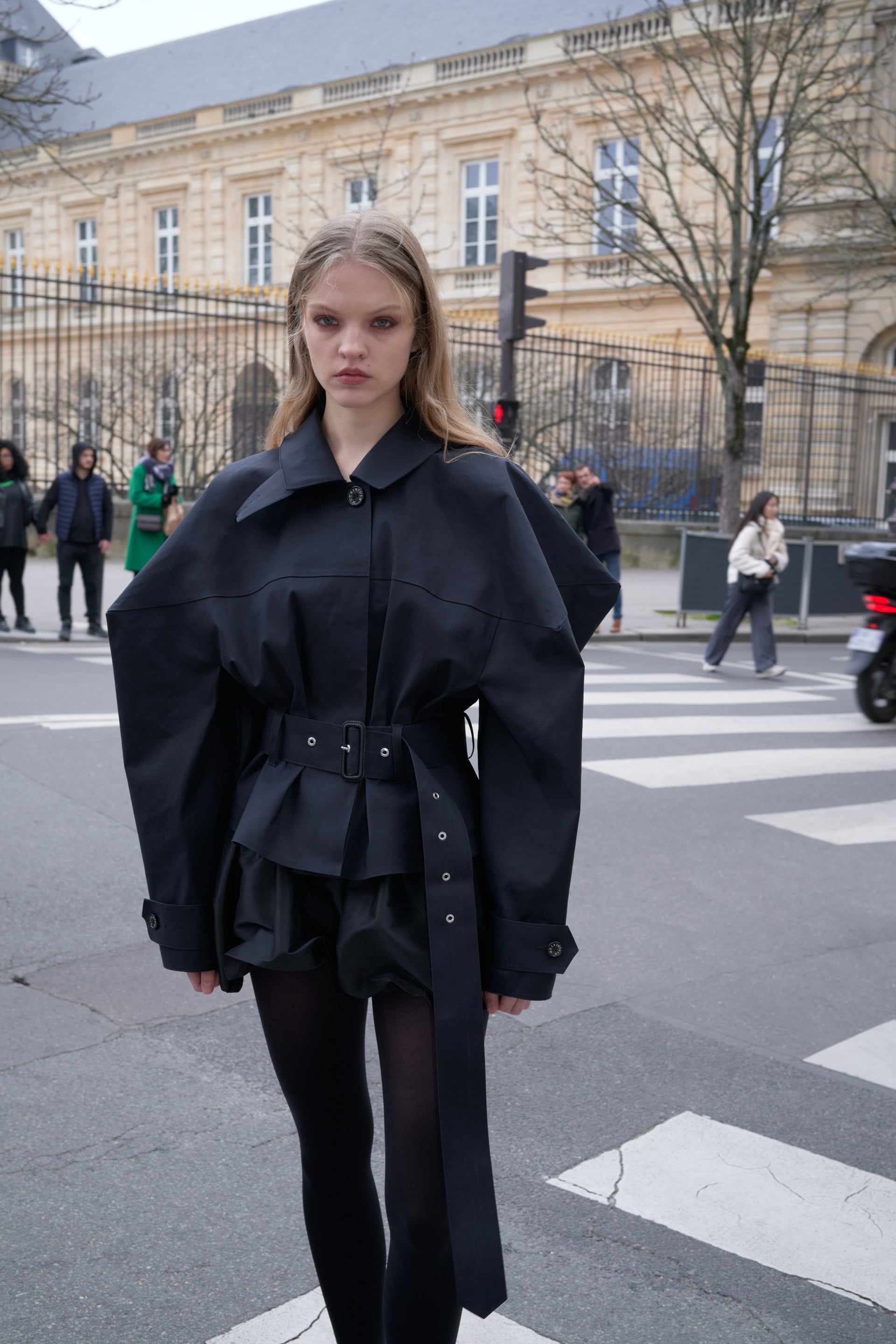 Woman in a black coat standing on a city street