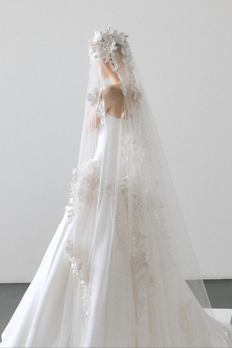 White wedding dress with a long veil on a plain background