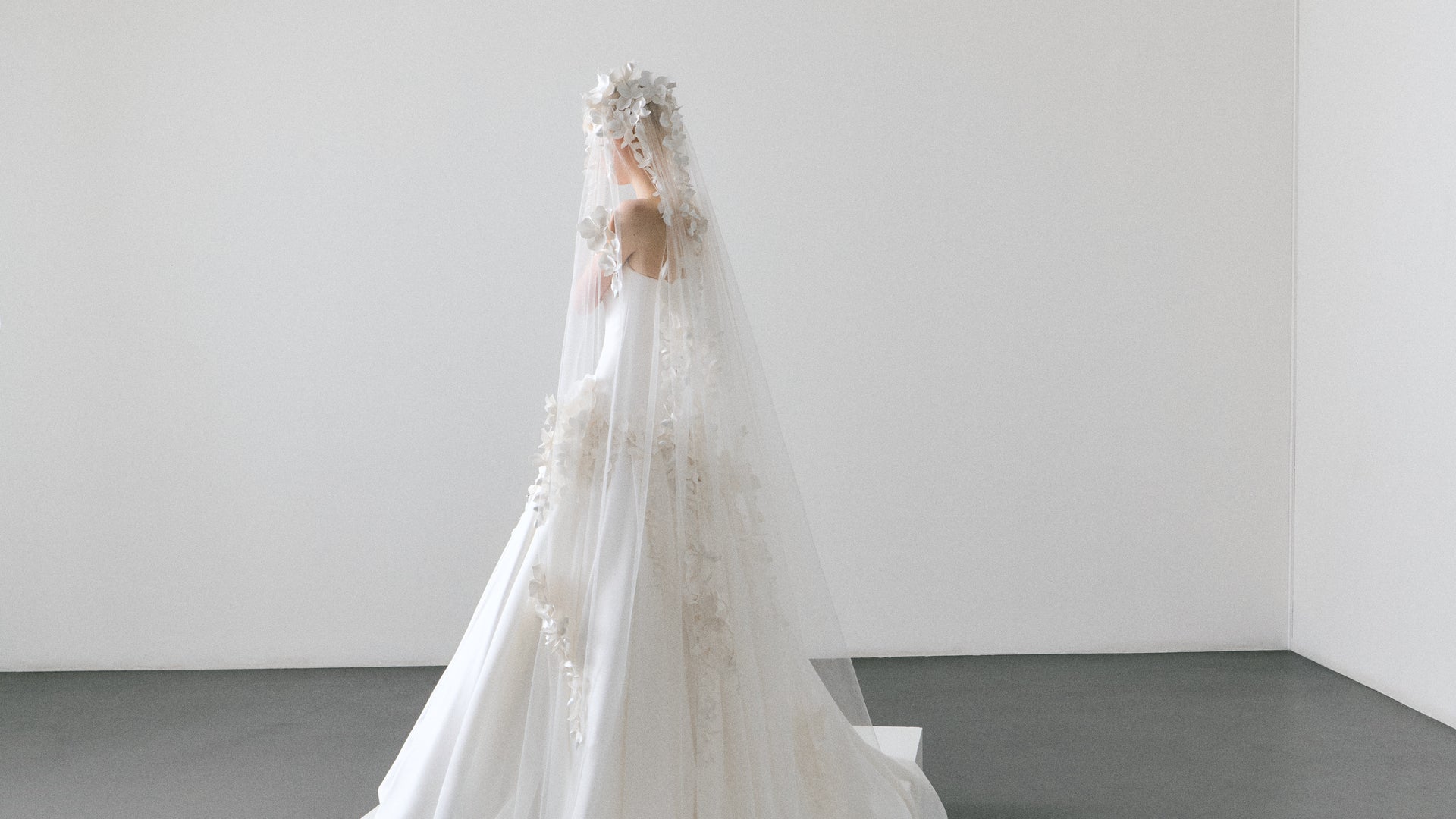 White wedding dress with a long veil on a plain background