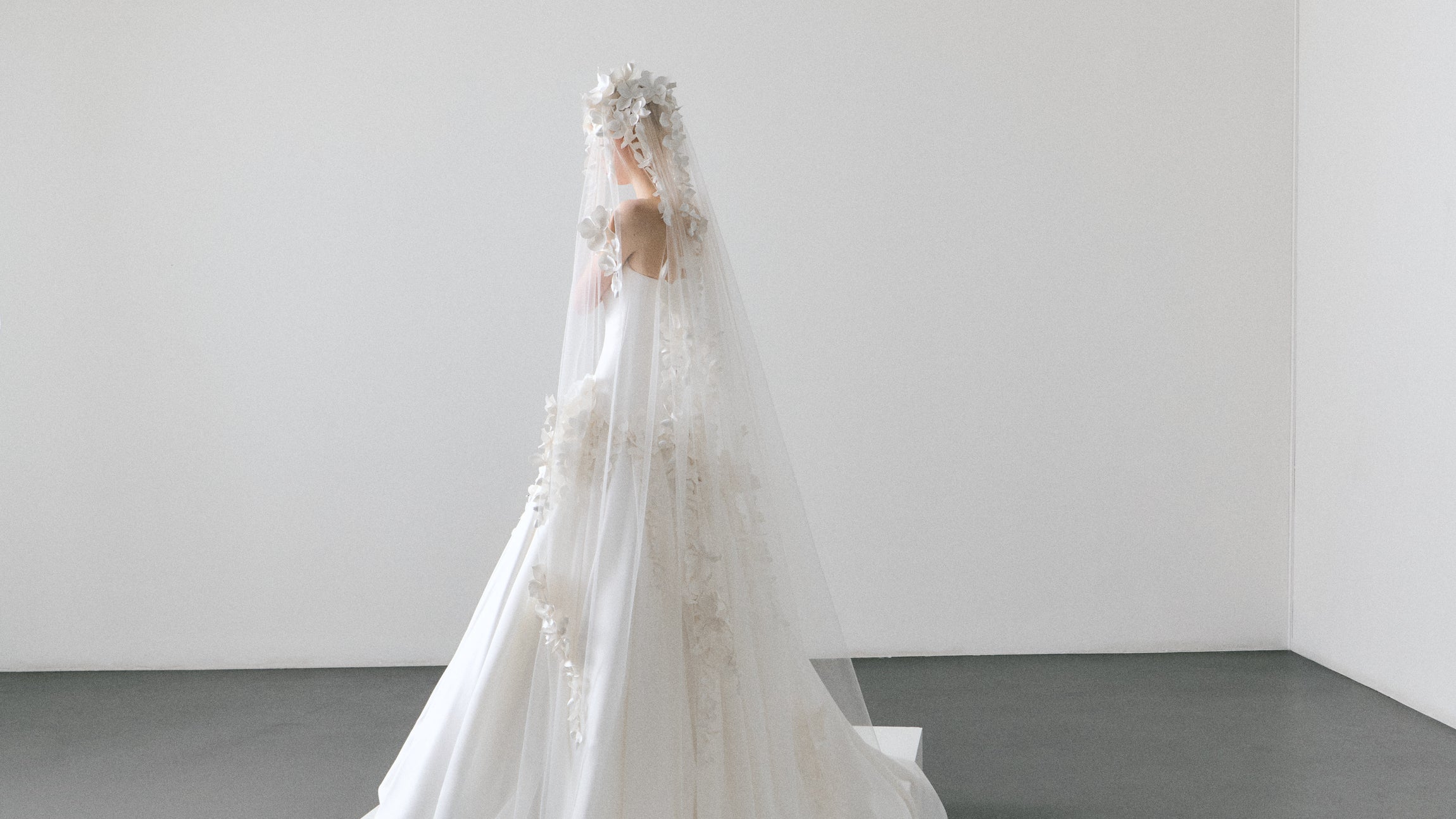White wedding dress with a long veil on a plain background