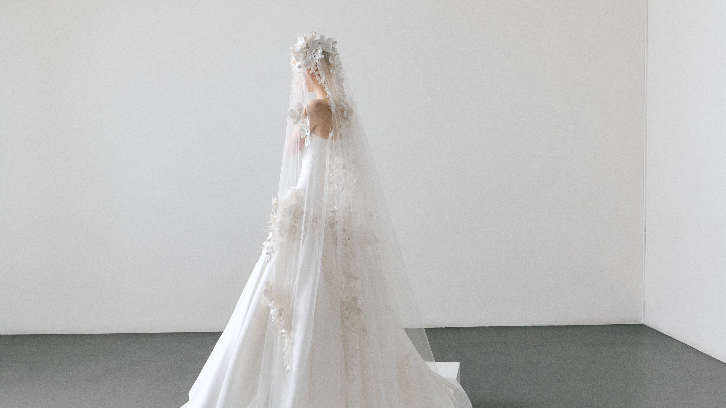 White wedding dress with a long veil on a plain background