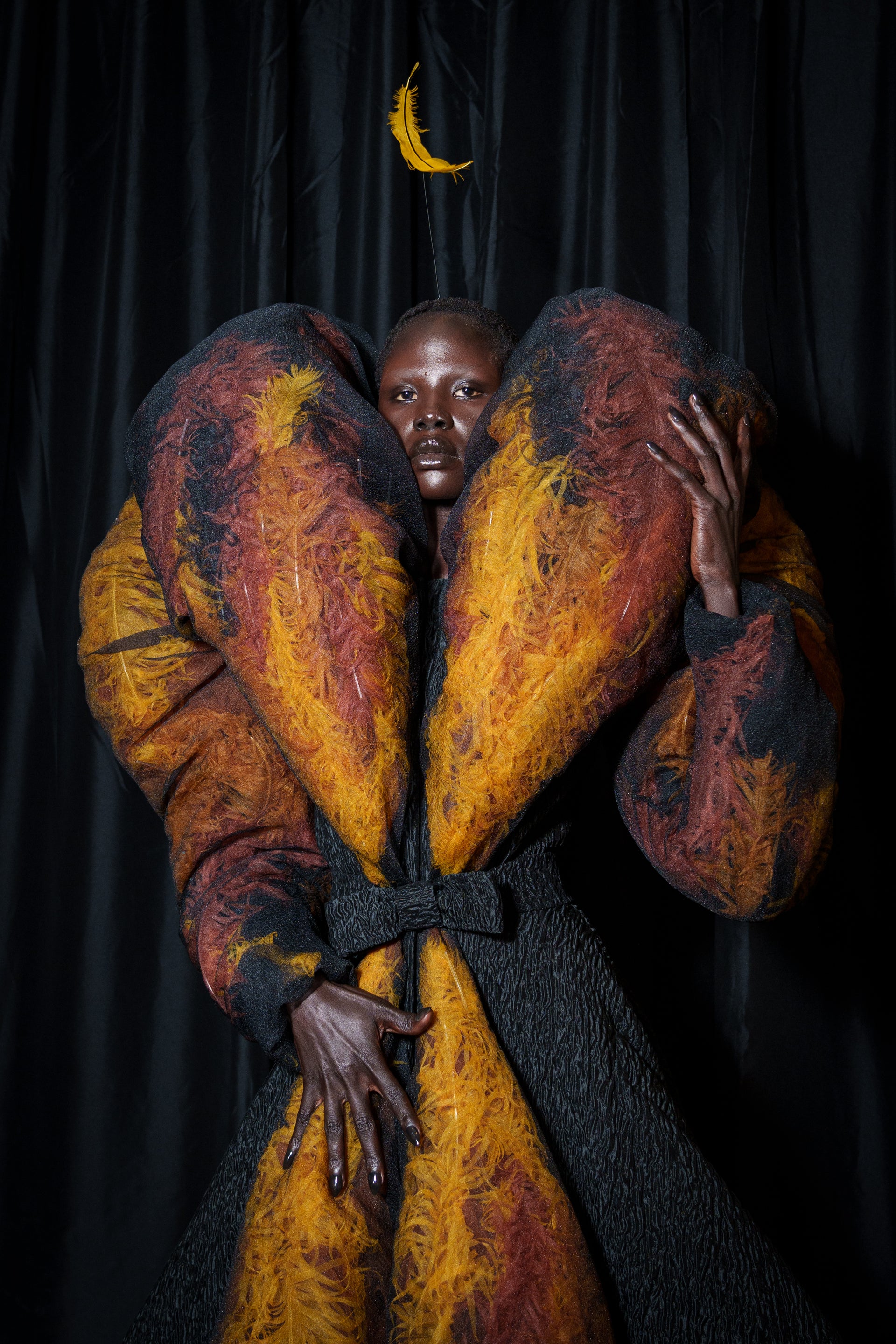 Person wearing a large, colorful coat and feather on the head 
