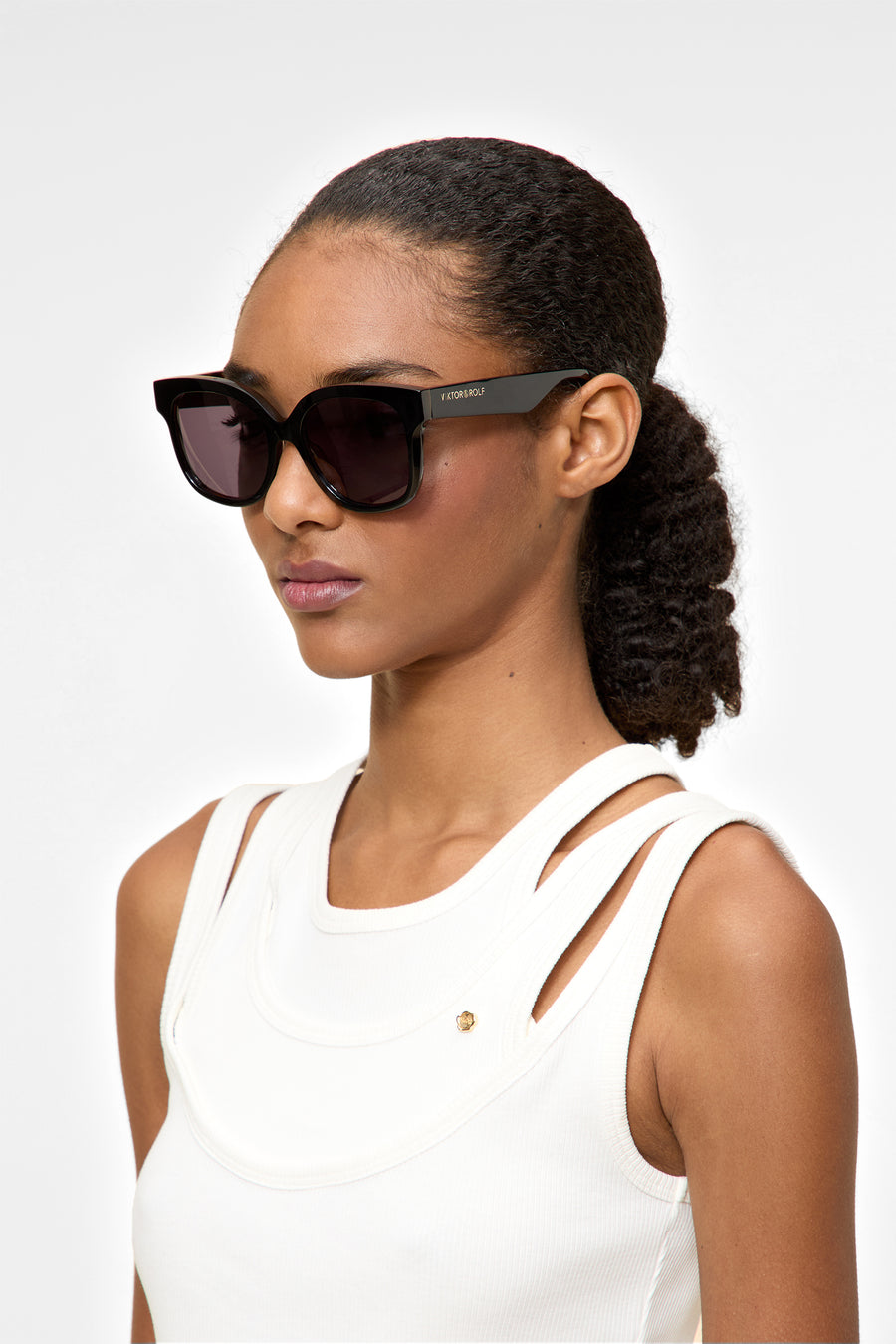 Woman wearing dark sunglasses with a white background