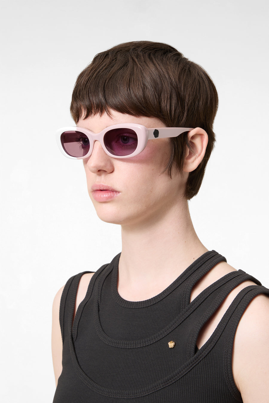 Model wearing light pink sunglasses on a white background.