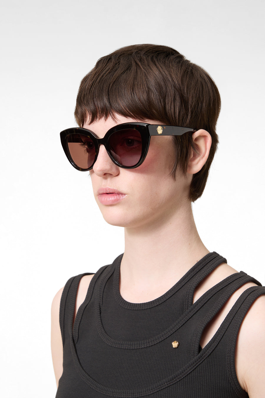Model wearing tortoise cat-eye sunglasses on a white background.