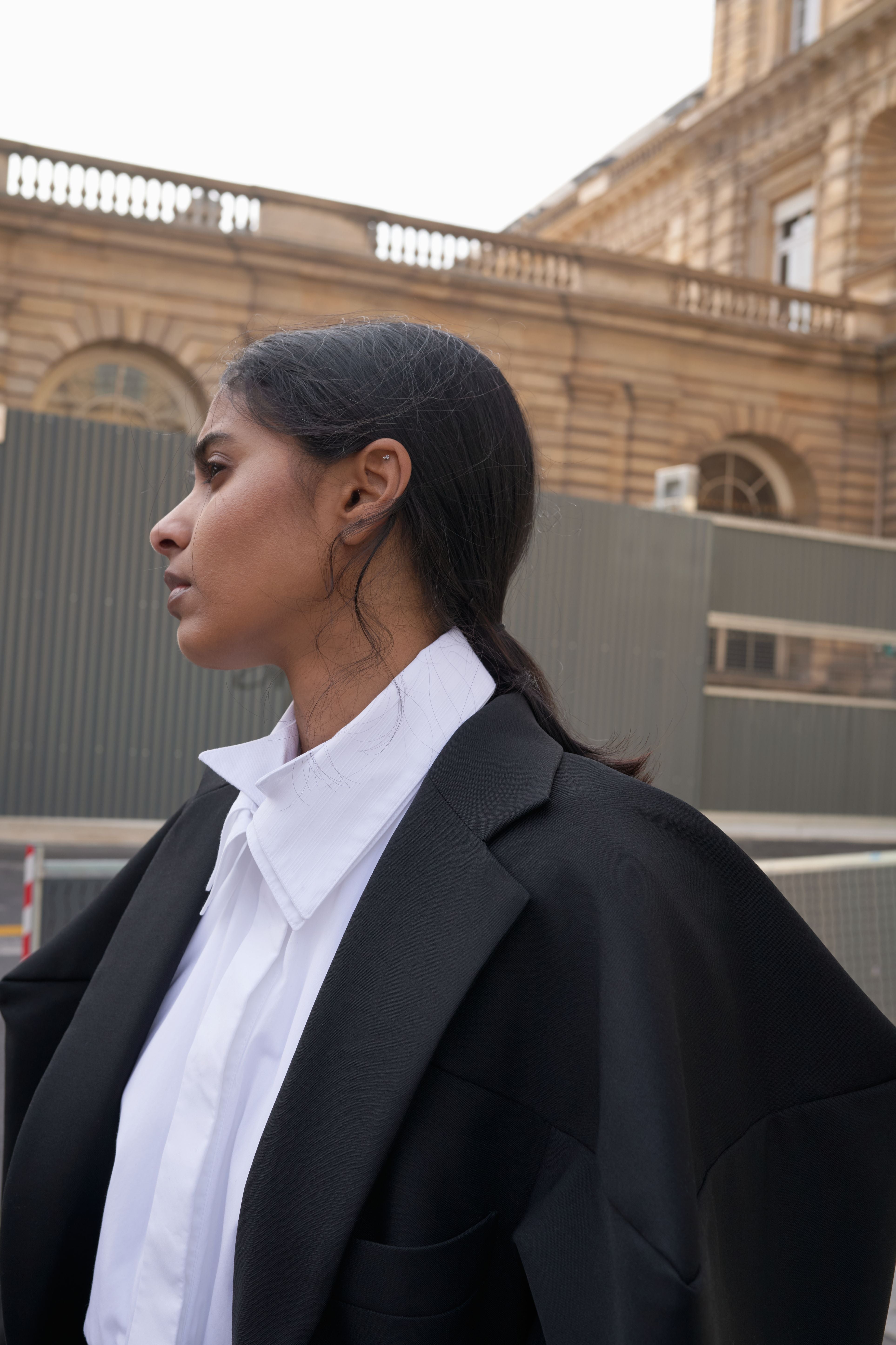 Woman in a black blazer and white shirt standing in front of a building