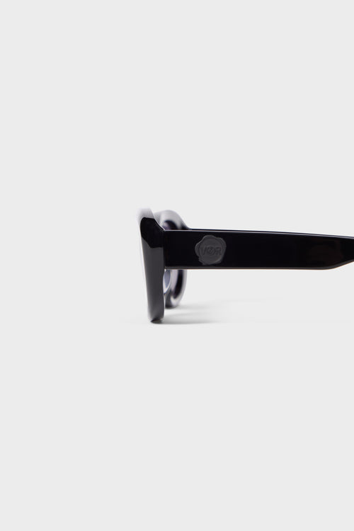 Stylish sunglasses with glossy black acetate frame, showcasing a minimalist design with subtle embossed logo detail on the arm.