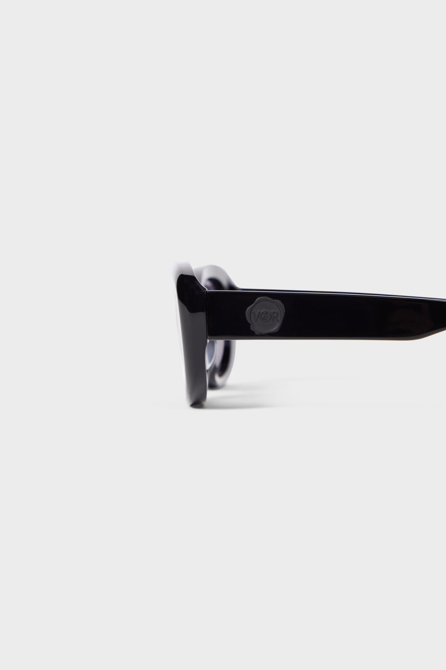 Stylish sunglasses with glossy black acetate frame, showcasing a minimalist design with subtle embossed logo detail on the arm.