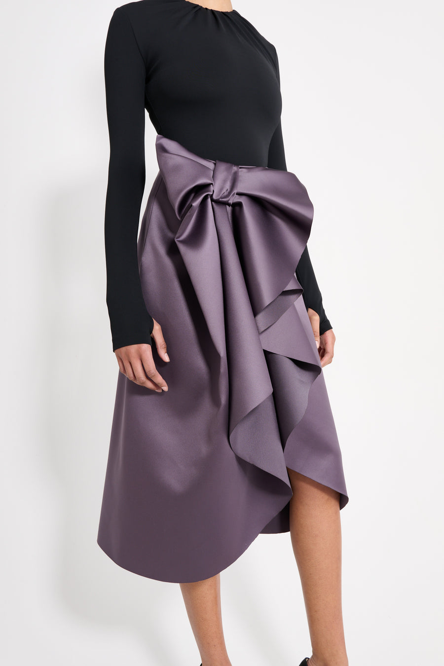 Model wearing a black drape body with a purple satin skirt.