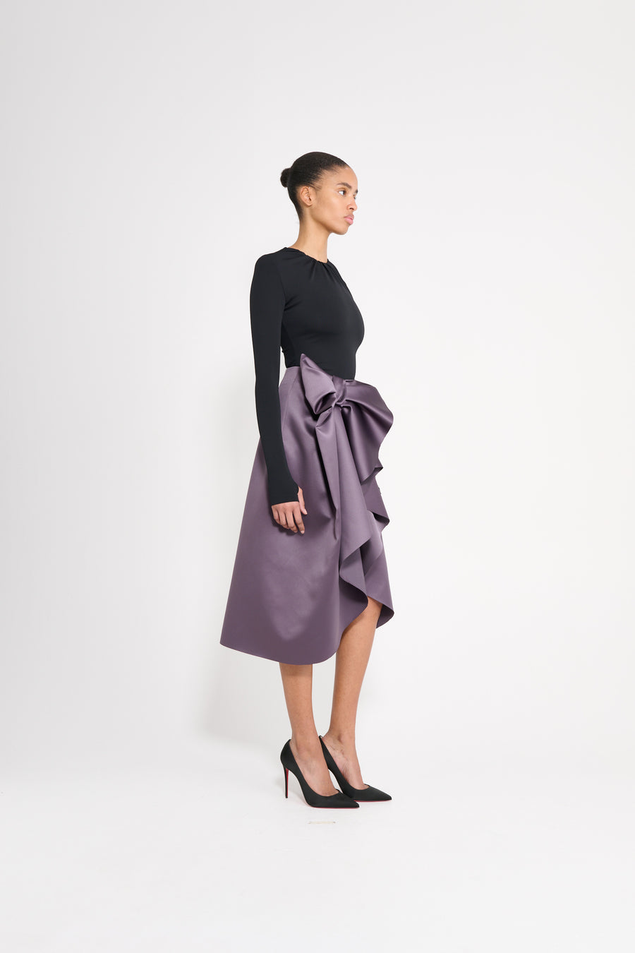 Model wearing a black drape body with a purple satin skirt.