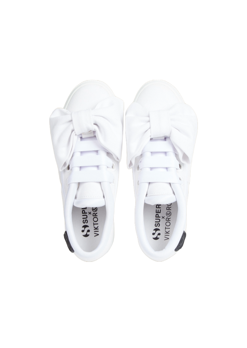 White sneakers featuring oversized bows, with a collaboration logo on the insole, offering a playful and stylish twist.