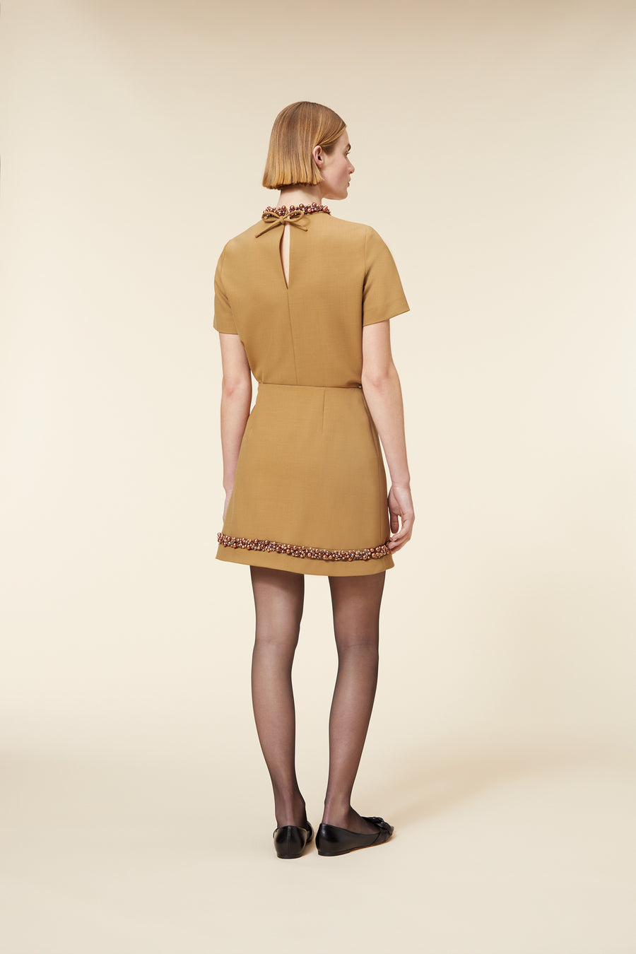 Tailored camel mini dress with ornate beaded trim and a chic back keyhole, exuding elegant and minimalist style.