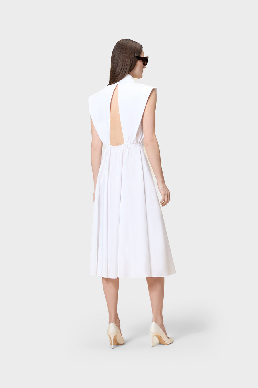 Woman wearing a white dress with cut-out back on a white background
