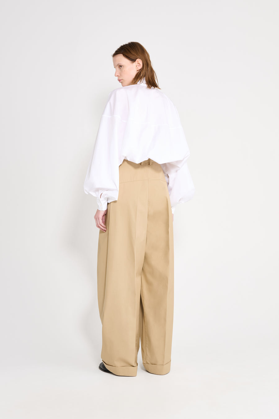 Person wearing a white shirt and beige pants on a white background