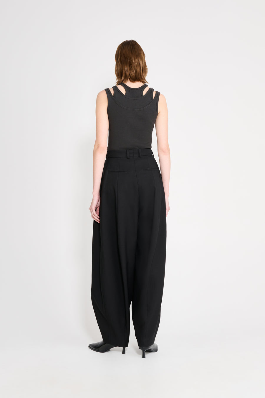 Person wearing a black sleeveless top and wide-leg pants on a white background