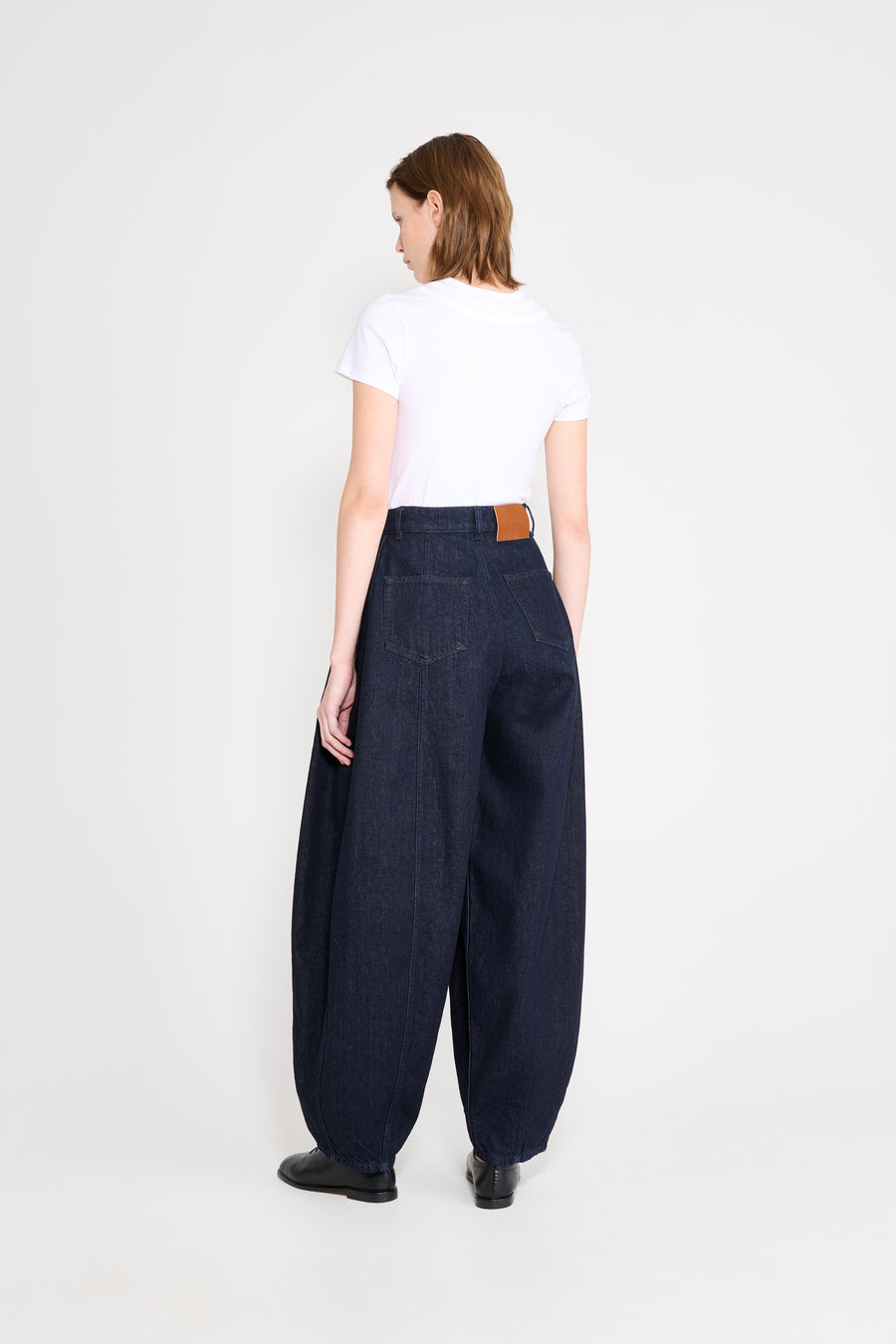 Person wearing a white t-shirt and dark blue wide-leg pants on a white background