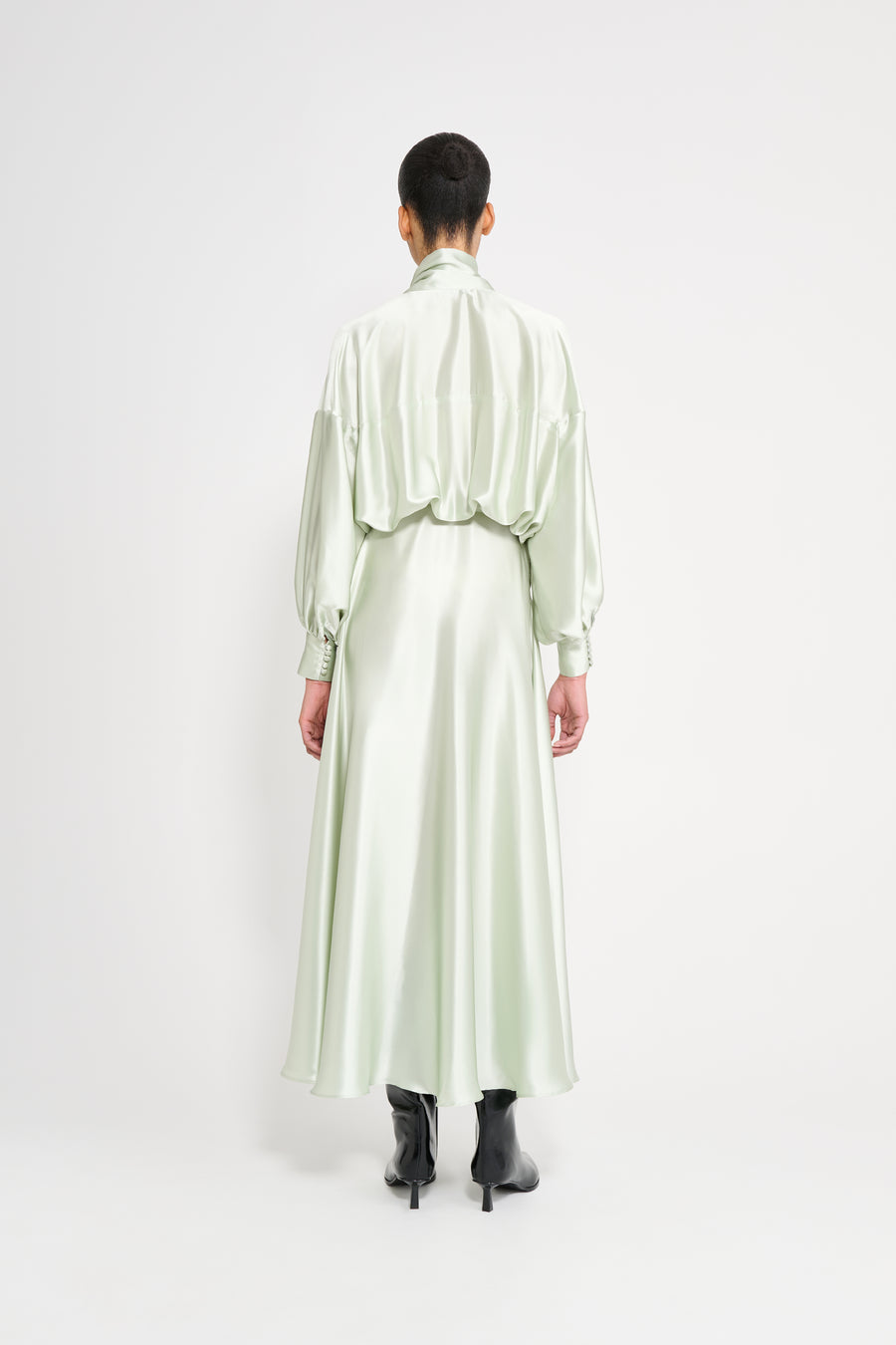Person wearing a light green satin dress on a white background