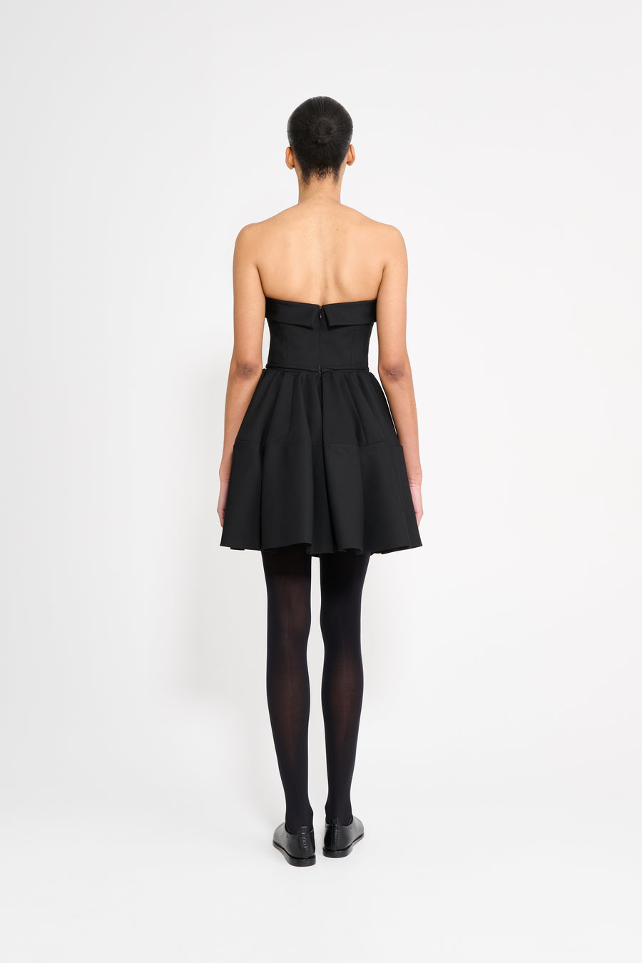 Person wearing a black strapless dress on a white background