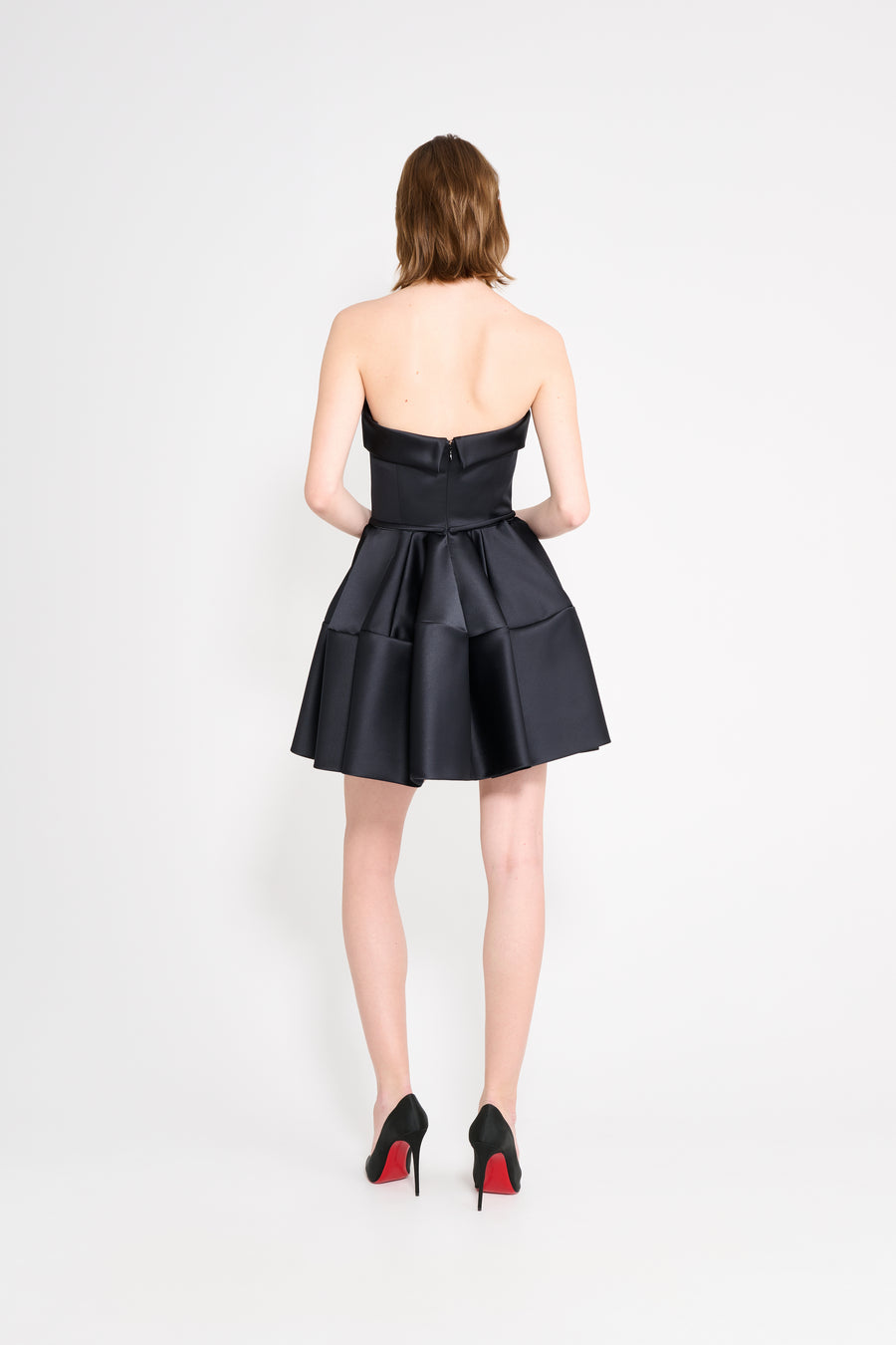 Model wearing a black mini dress on a white background.