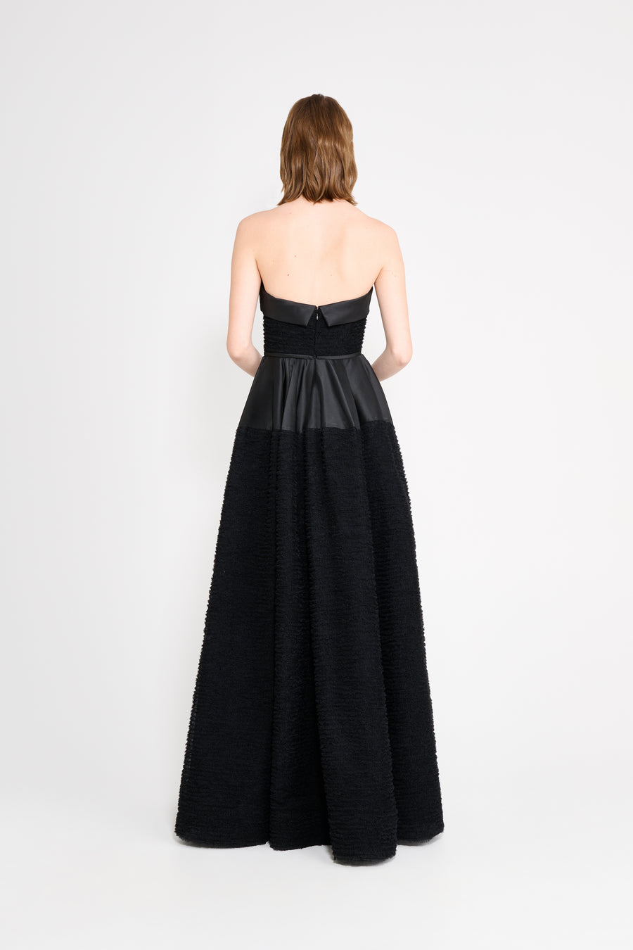 Woman wearing a black strapless gown on a white background