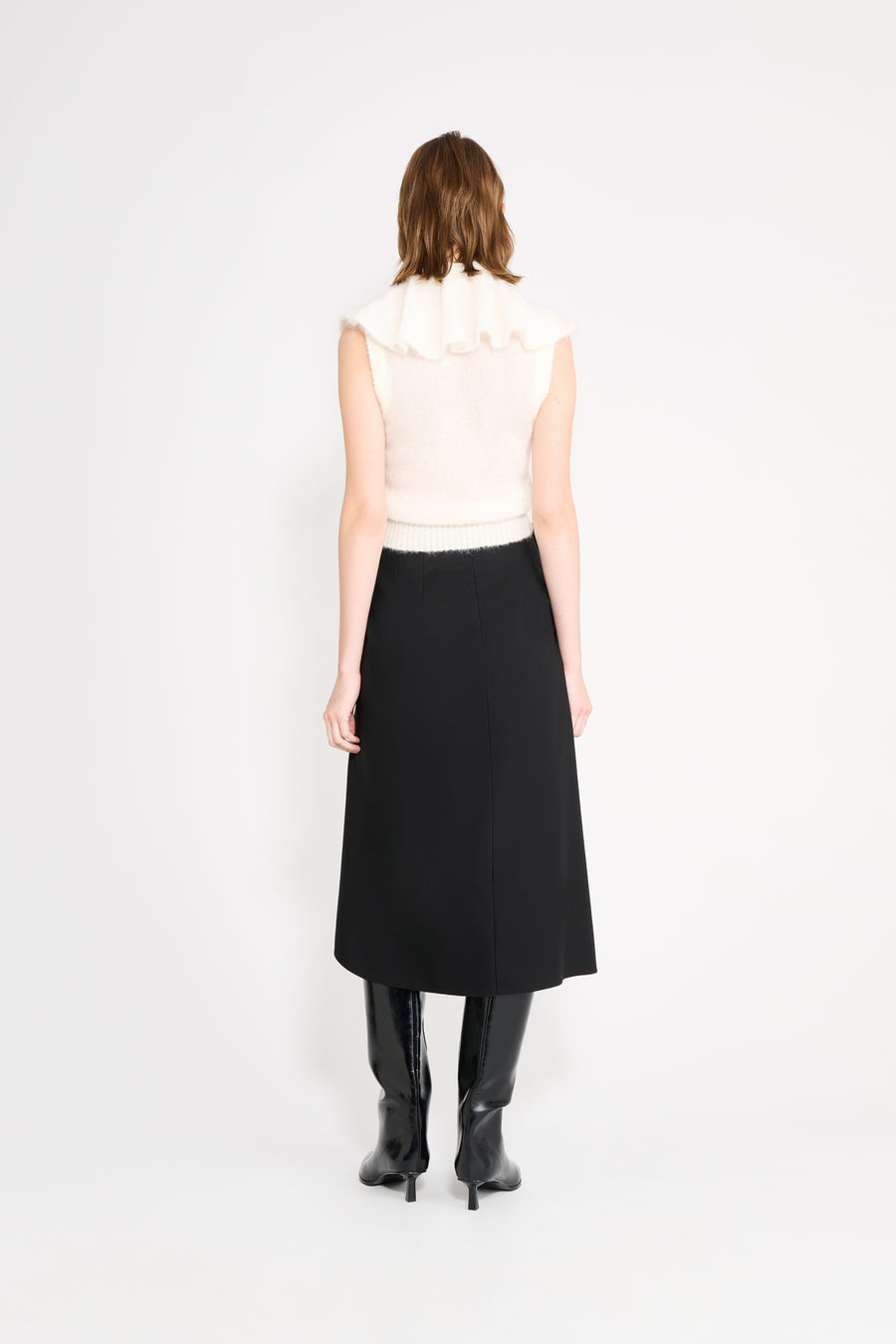 Model wearing a white volant neck top shown from the back.