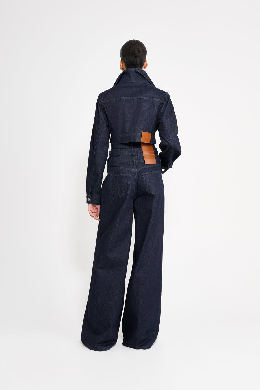 Person wearing a dark denim outfit with a white background