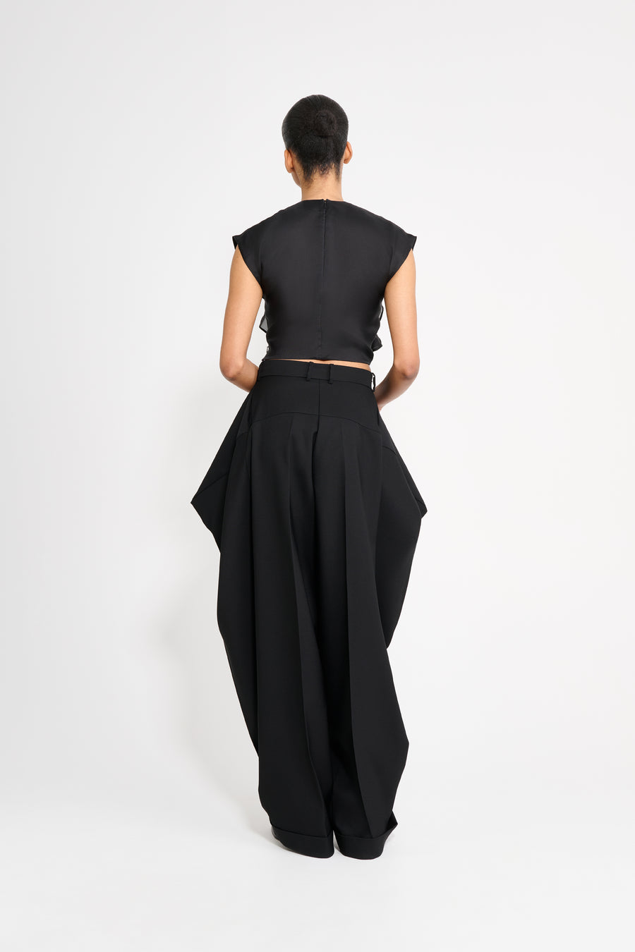 Person wearing a black outfit with a high-low hem on a white background