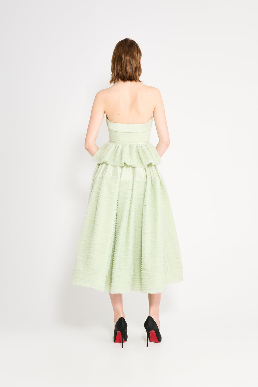 Woman wearing a light green strapless dress on a white background