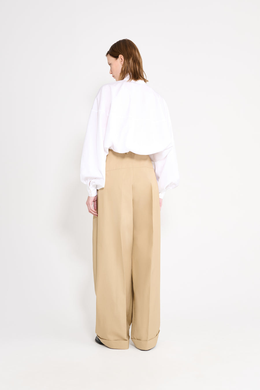 Person wearing a white shirt and beige pants on a white background